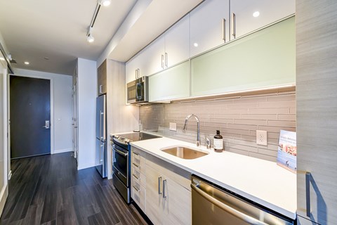 A modern kitchen with a white countertop and stainless steel appliances.