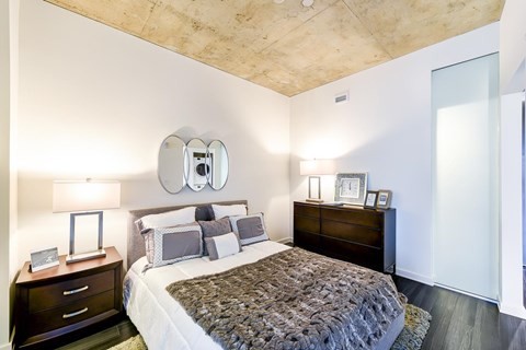 A bedroom with a bed, nightstand, and lamp.