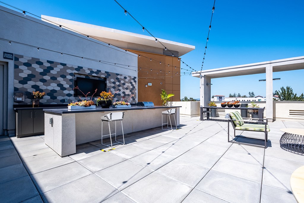 a patio with a bar and a dining area with chairs and a table