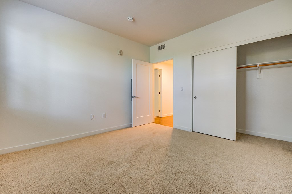 an empty living room with white walls and a door to a closet