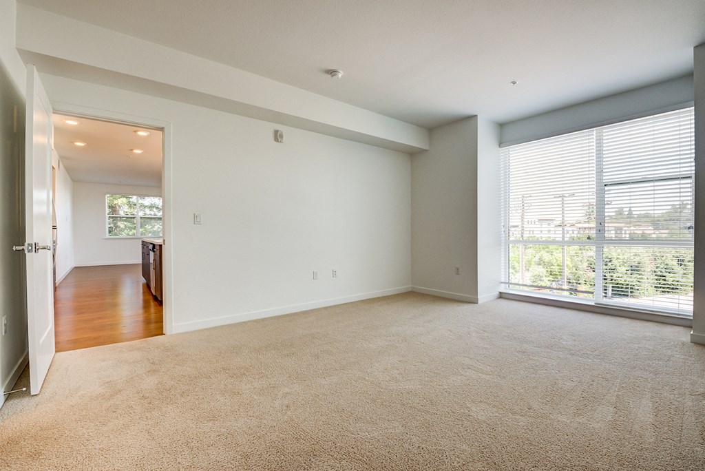 an empty living room with a large window and a door