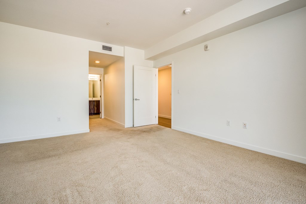 an empty living room with white walls and carpet
