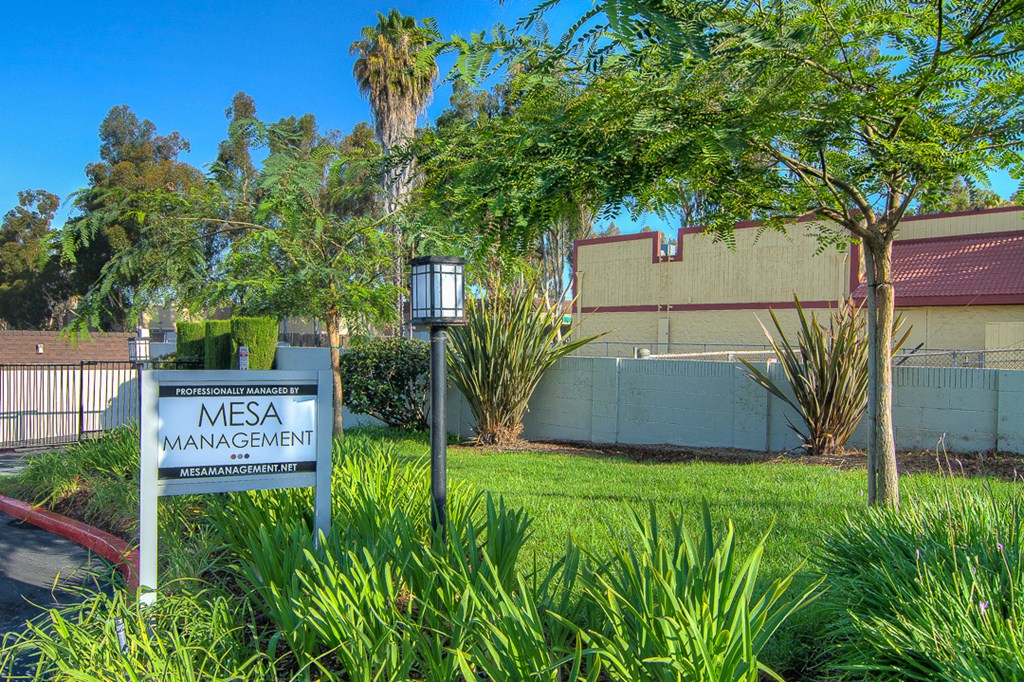 a sign in the grass in front of a building