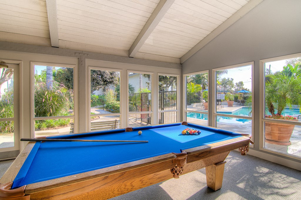 a pool table in a screened in porch with a swimming pool