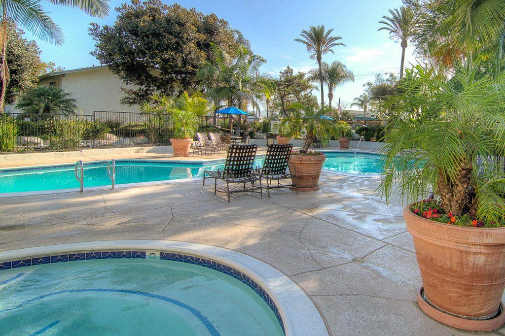 a swimming pool with chairs and potted plants next to it
