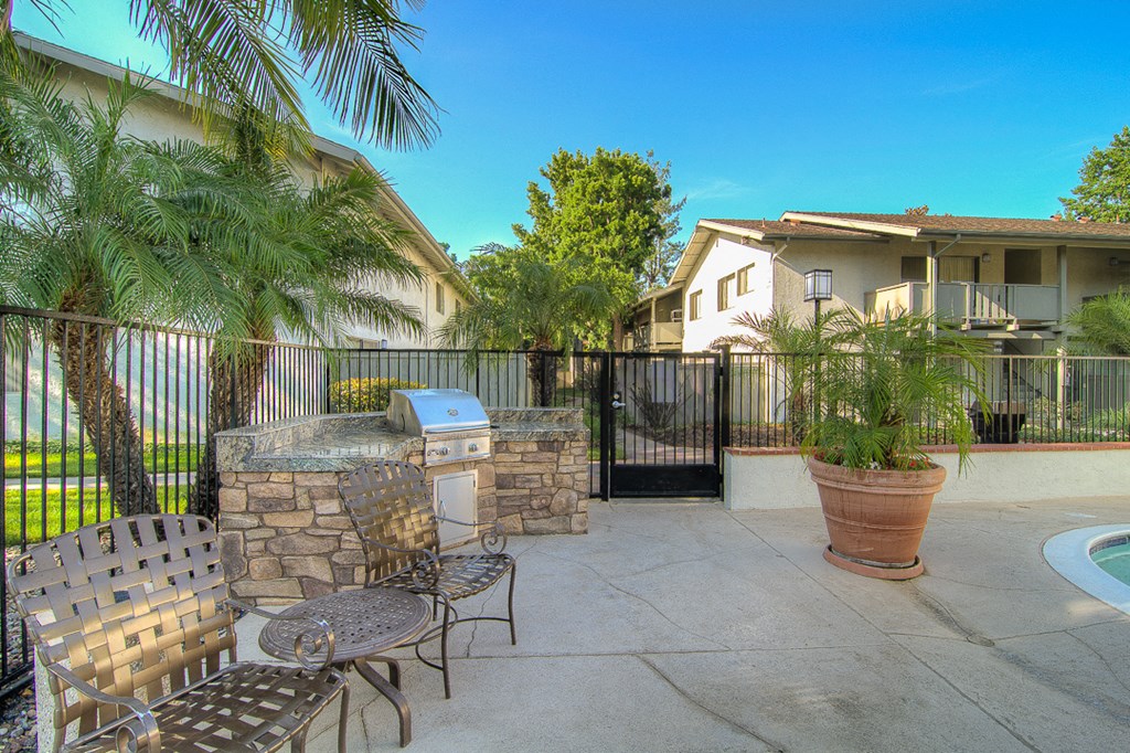 a patio with a grill and chairs and a swimming pool