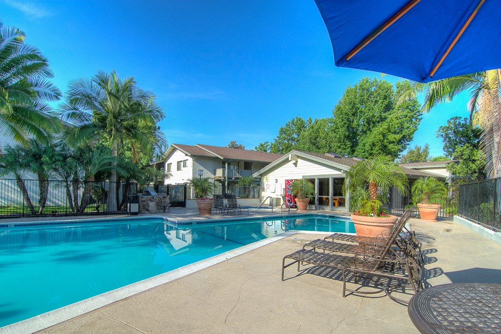 a swimming pool with chairs and a house in the background