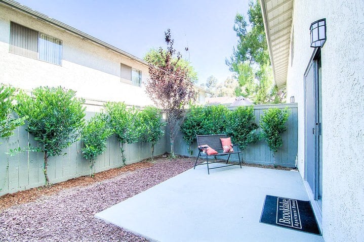 a patio with a bench and a chair in front of a fence