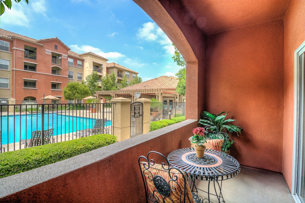 a balcony with a table and chairs overlooking a swimming pool