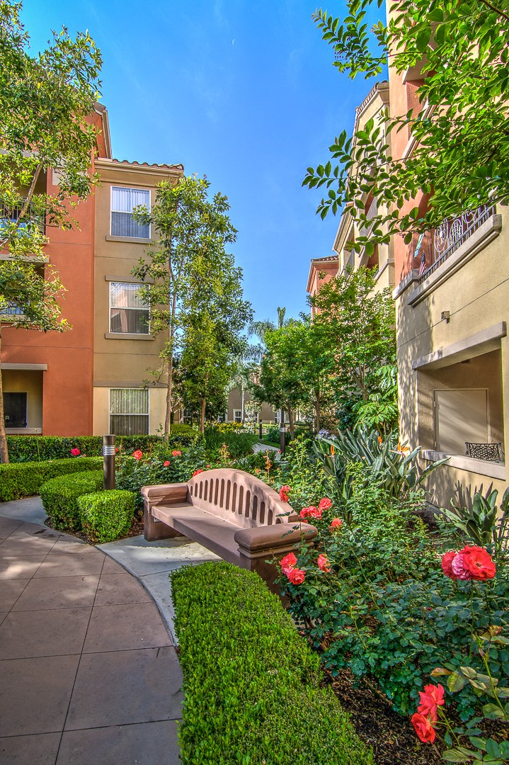 a wooden bench in a garden in front of an apartment building