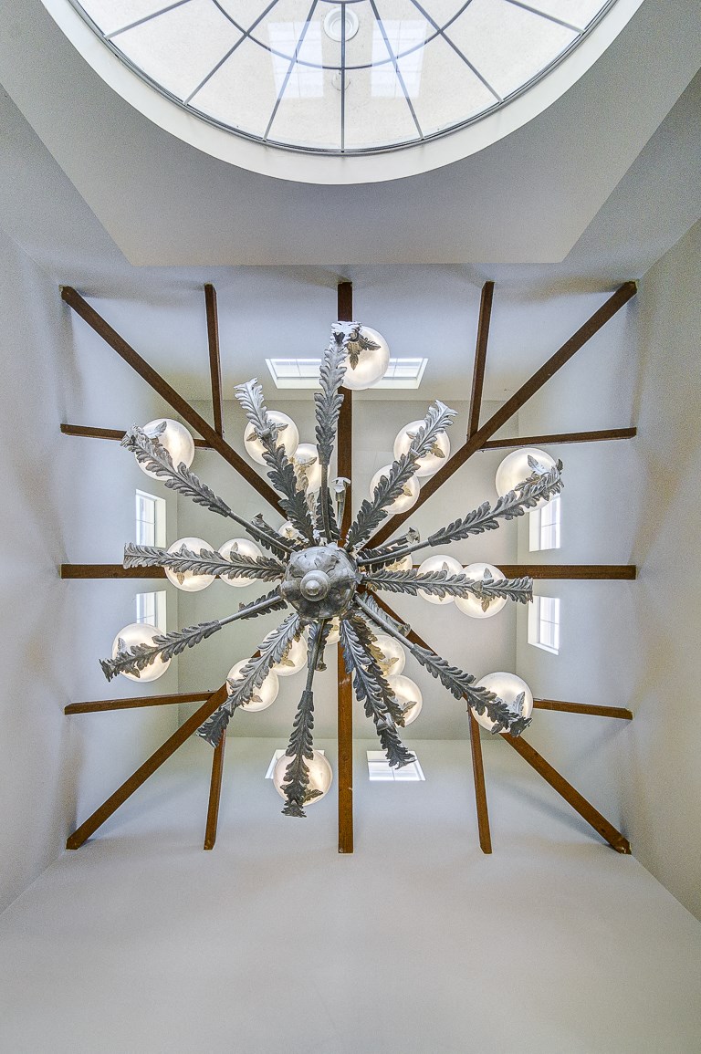 a chandelier hangs from the ceiling in a room with a skylight