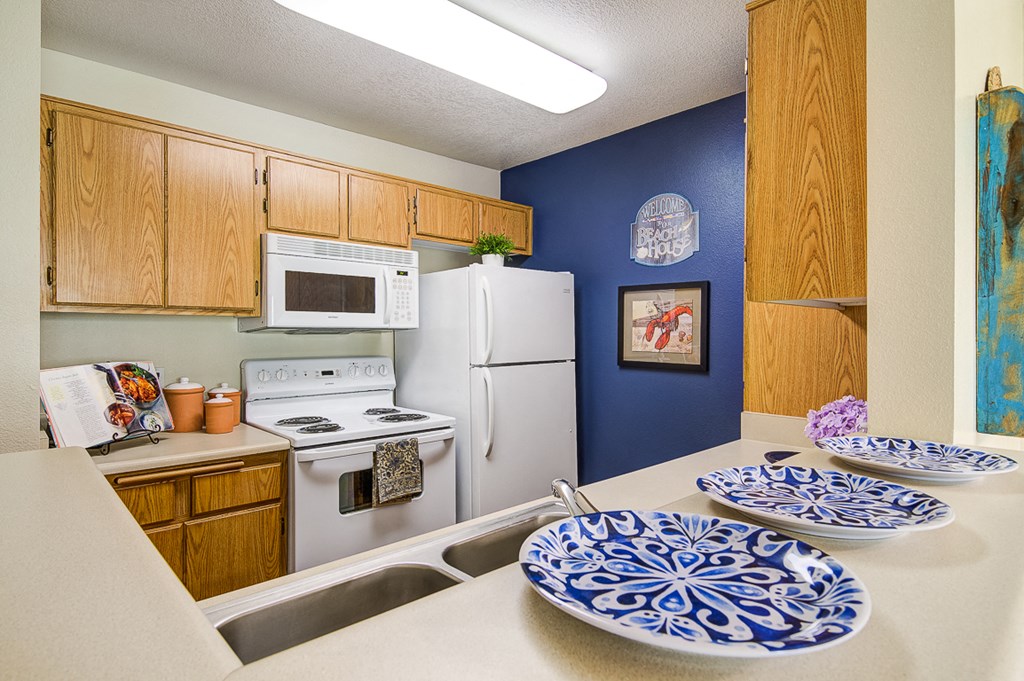 full kitchen with white appliances and blue and white plates on the counter