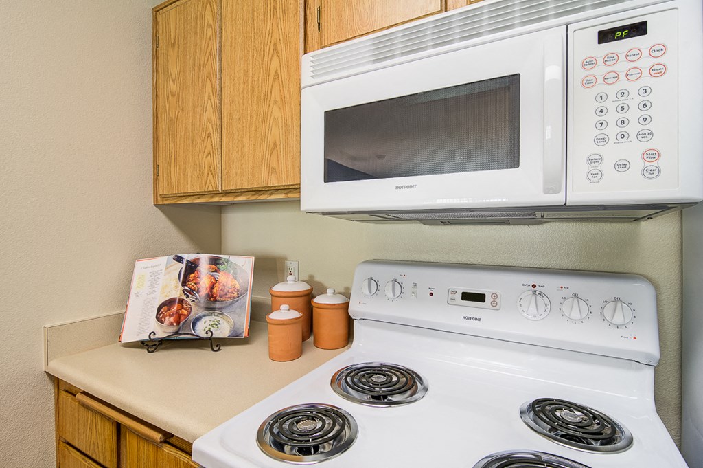 a kitchen with a white stove and a microwave above it