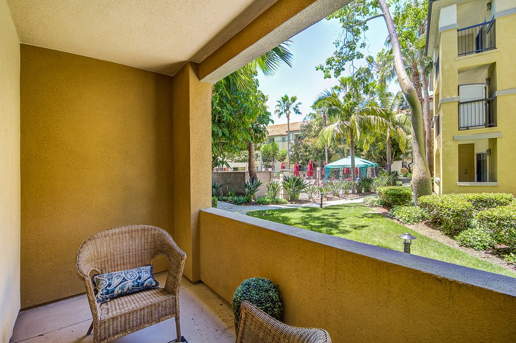 a balcony with two chairs and a view of a garden