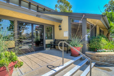 the entrance to a building with stairs and a patio with potted plants