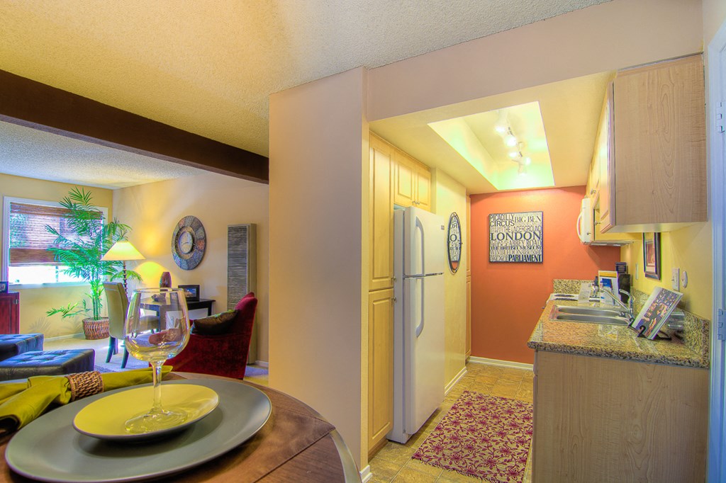 a kitchen and living room with a table with a glass of wine