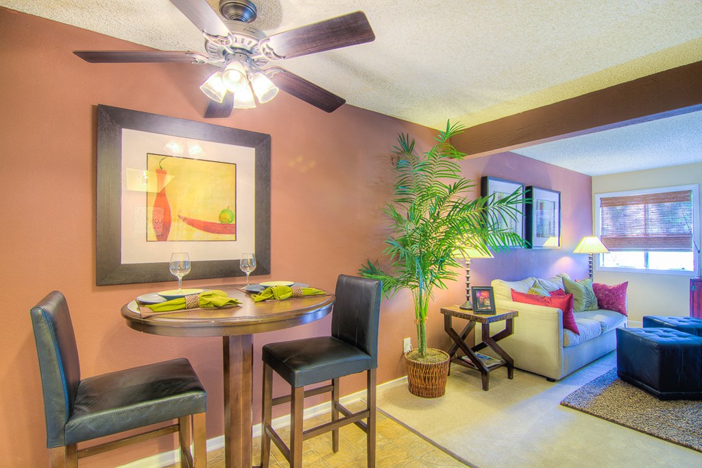 a living room with a table and chairs and a ceiling fan