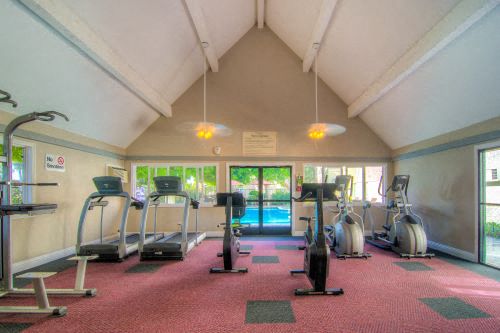 a gym with a pool and exercise equipment in a room