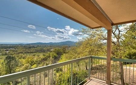 a balcony with a view of the trees and mountains