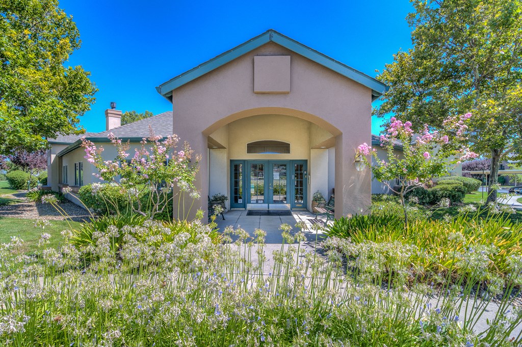 the front of a house with a walkway and flowers in the yard