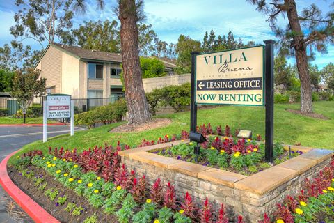 the villa at leasing office sign with flowers in front of a building