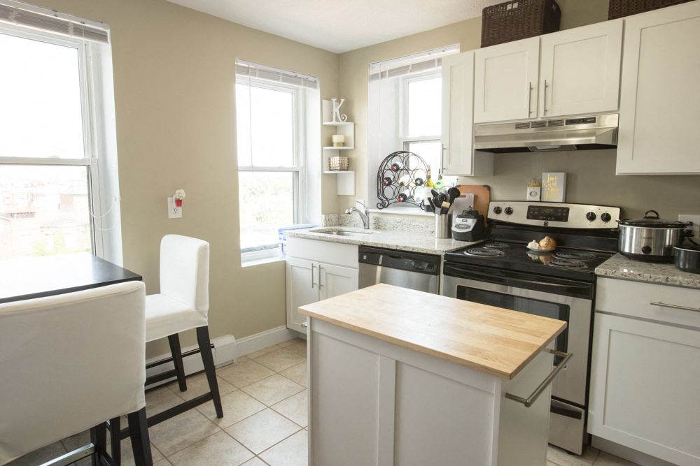 a white kitchen with a butcher block island and stainless steel appliances
