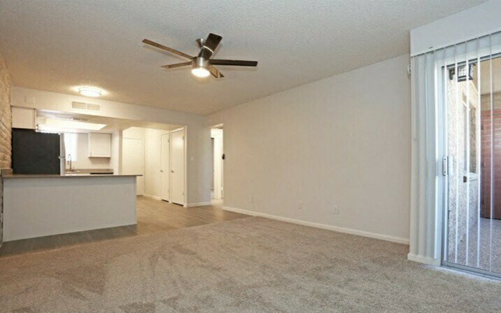an empty living room and kitchen with a ceiling fan