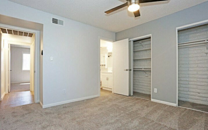 an empty living room with a closet and a ceiling fan