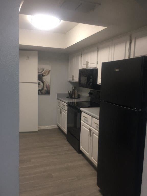 a kitchen with white cabinets and a black refrigerator