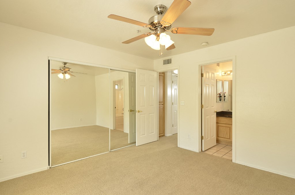 a bedroom with a ceiling fan and a mirror
