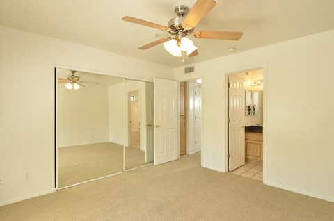 a bedroom with a ceiling fan and a mirror