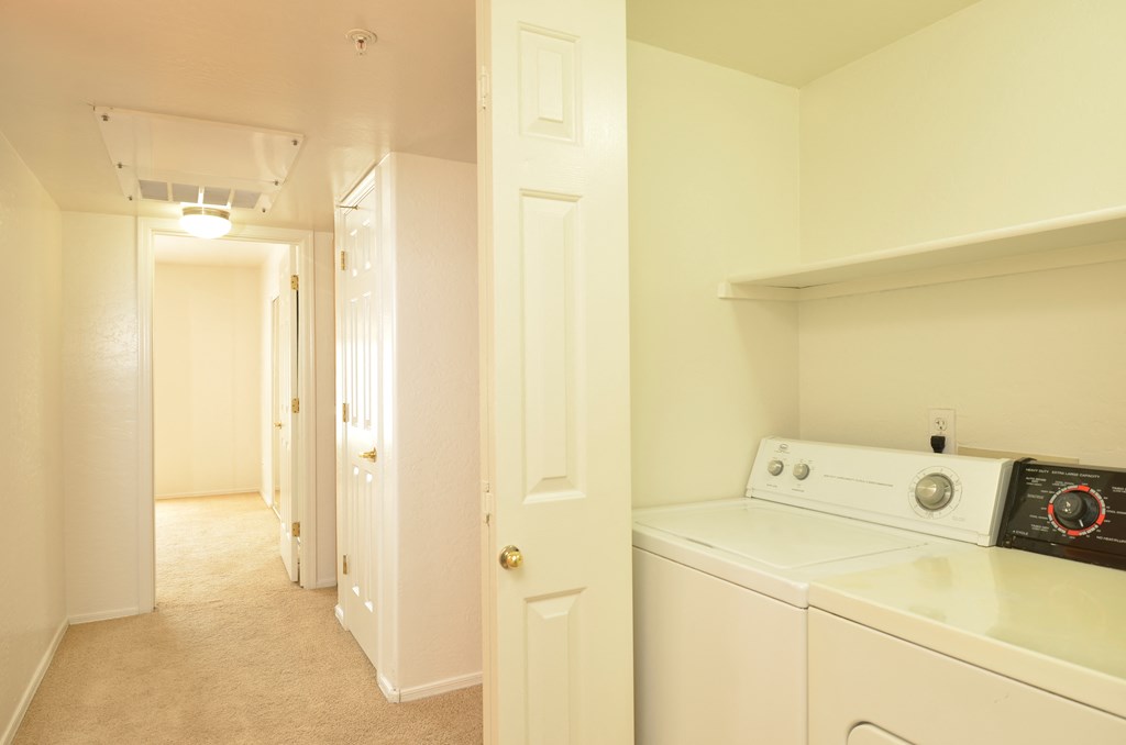 a laundry room with a washer and dryer and a hallway with a door