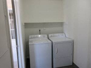two washing machines in a small room with a door