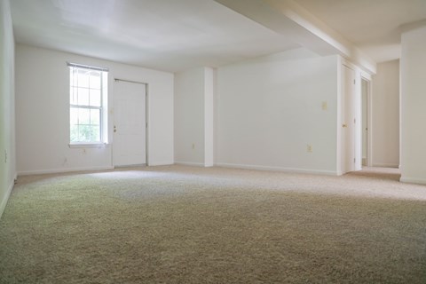 an empty living room with white walls and carpet
