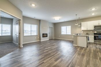 Open living and dining area with hard wood style flooring looking into kitchen at The Villas at Falling Waters in Omaha, NE