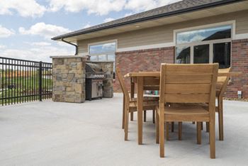 A patio with a table and chairs and a stone fireplace.