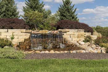 A small waterfall in a garden surrounded by rocks and greenery.