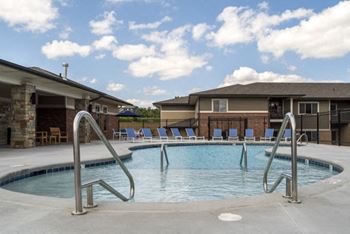 A swimming pool with a metal ladder and a building in the background.