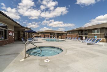 A swimming pool area with sun loungers and a building in the background.