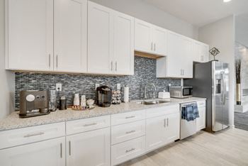 A kitchen with white cabinets and a granite countertop.