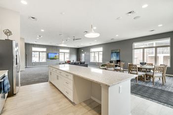 A kitchen with a refrigerator, island, and dining table.