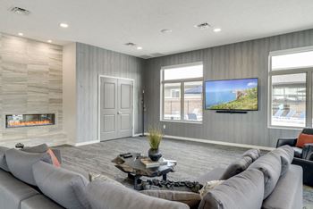 A modern living room with grey couches and a stone fireplace.