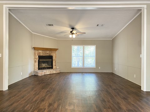 an empty living room with a fireplace and a ceiling fan