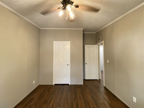 an empty living room with a ceiling fan and doors