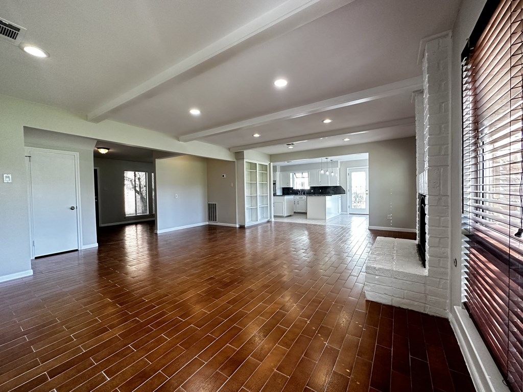 an empty living room with wood flooring and white walls