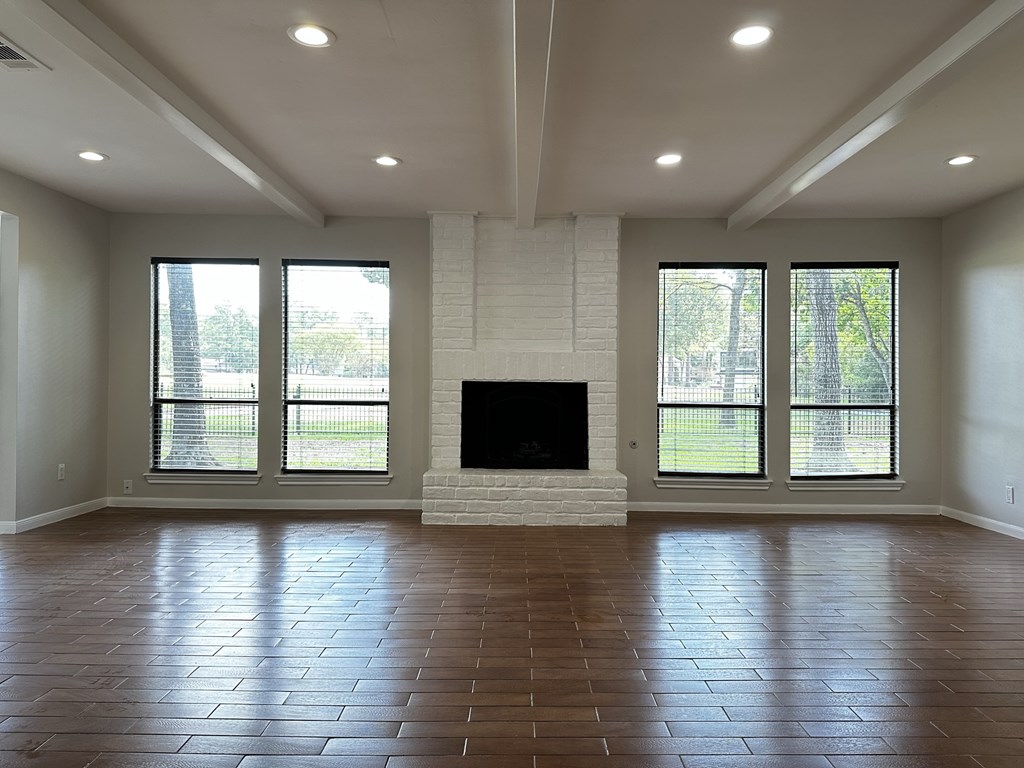 an empty living room with a fireplace and windows