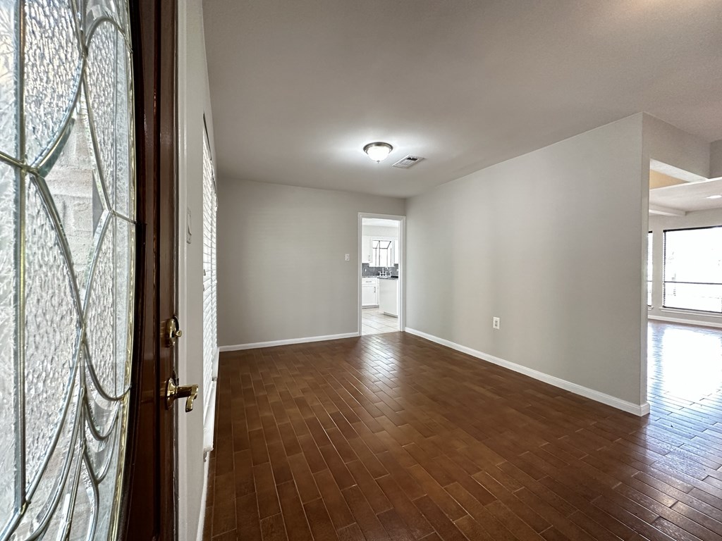 the living room and dining room of an empty home with wood flooring