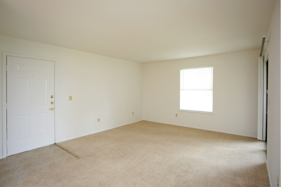 an empty room with a white door and a window