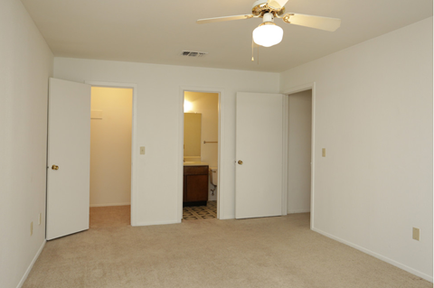 an empty living room with a ceiling fan and a closet
