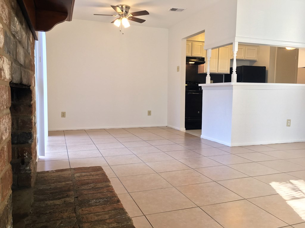an empty living room with a tile floor and a kitchen